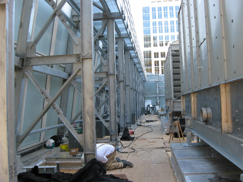 Galvanized structural steel framing and ductwork on a rooftop between office towers