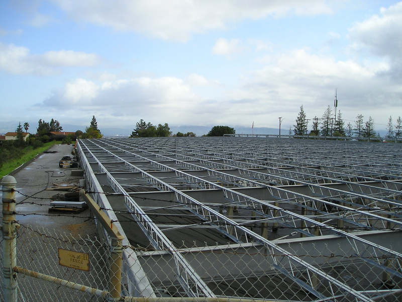 A large field of galvanized solar carport racking under an open sky